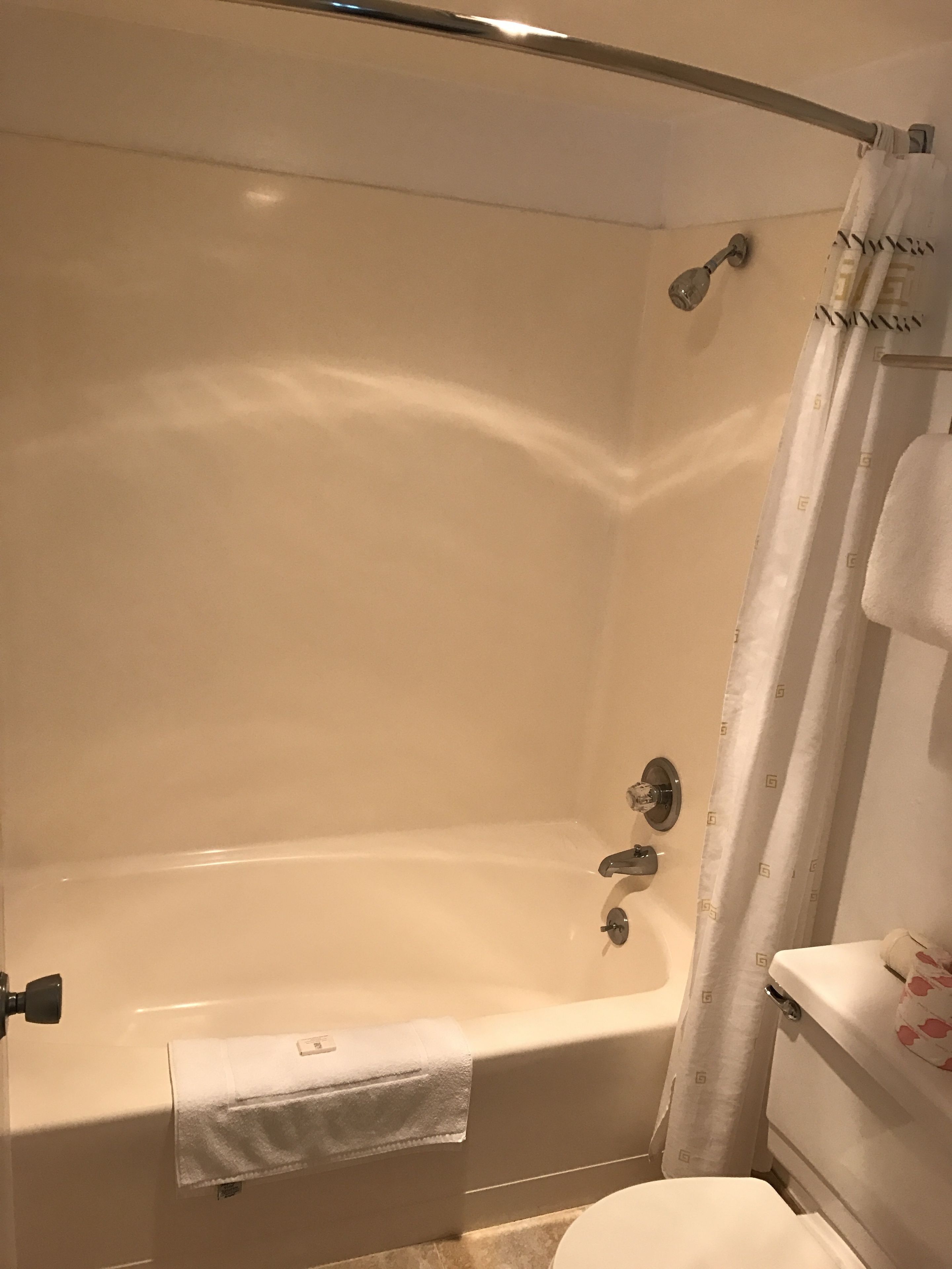A bathroom with a bathtub, toilet, and shower curtain.