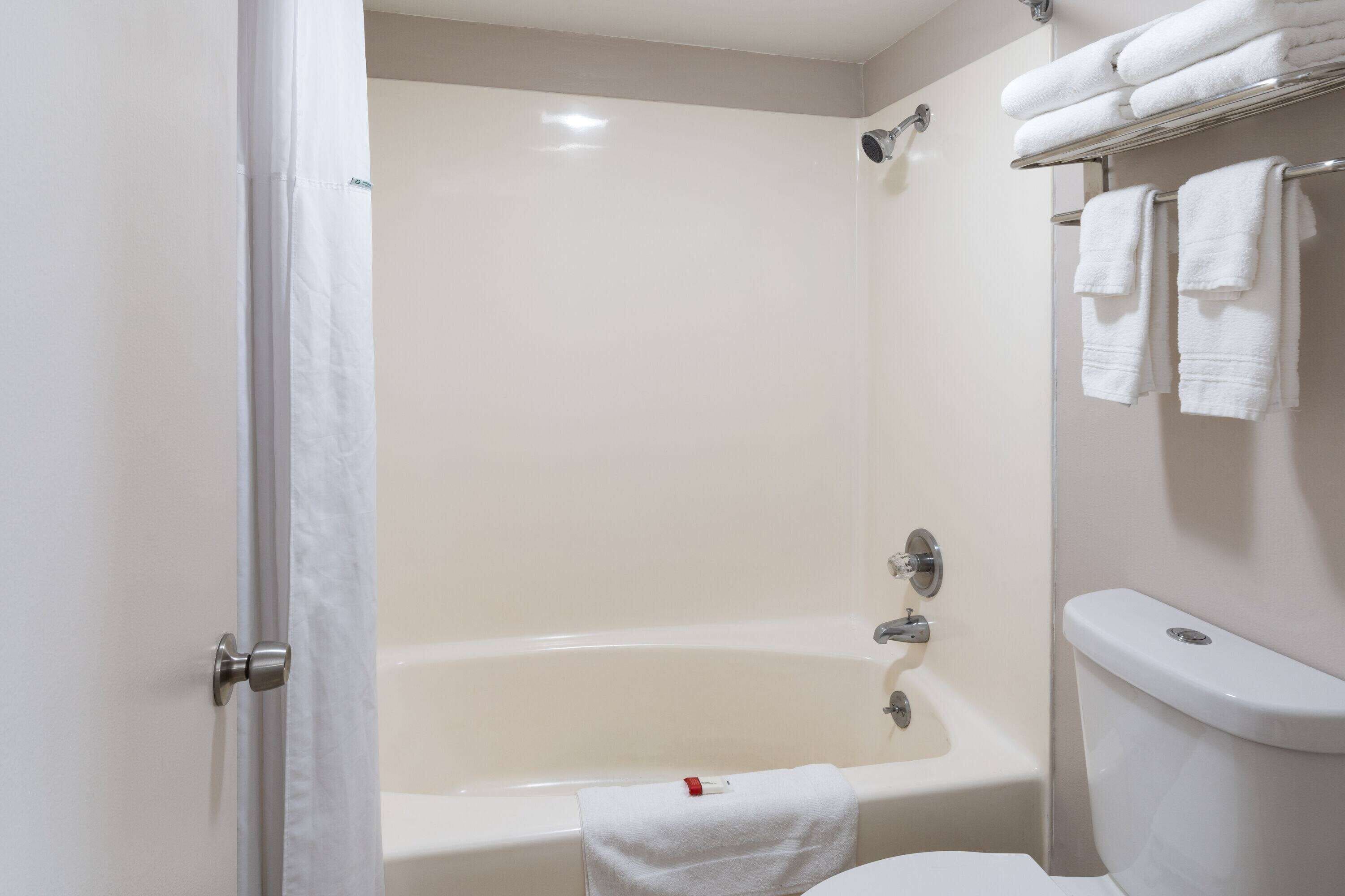 A bathroom with a bathtub, toilet, and towel rack.