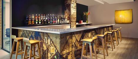 Un moderno bar con una barra larga, varios taburetes y una amplia variedad de botellas.