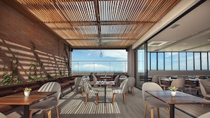 A modern meeting room with wooden tables and chairs, a high ceiling with a wooden slatted design, and a view of the cityscape through large windows. - Hotel Sites Monteria (Montería)