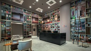 A spacious library with high ceilings, multiple bookshelves, a comfortable seating area, and a central reception desk. - Hotel Sites Monteria (Montería)