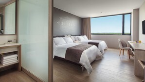 A modern hotel room with two beds, a desk, and a large window offering a view of the landscape. - Hotel Sites Monteria (Montería)
