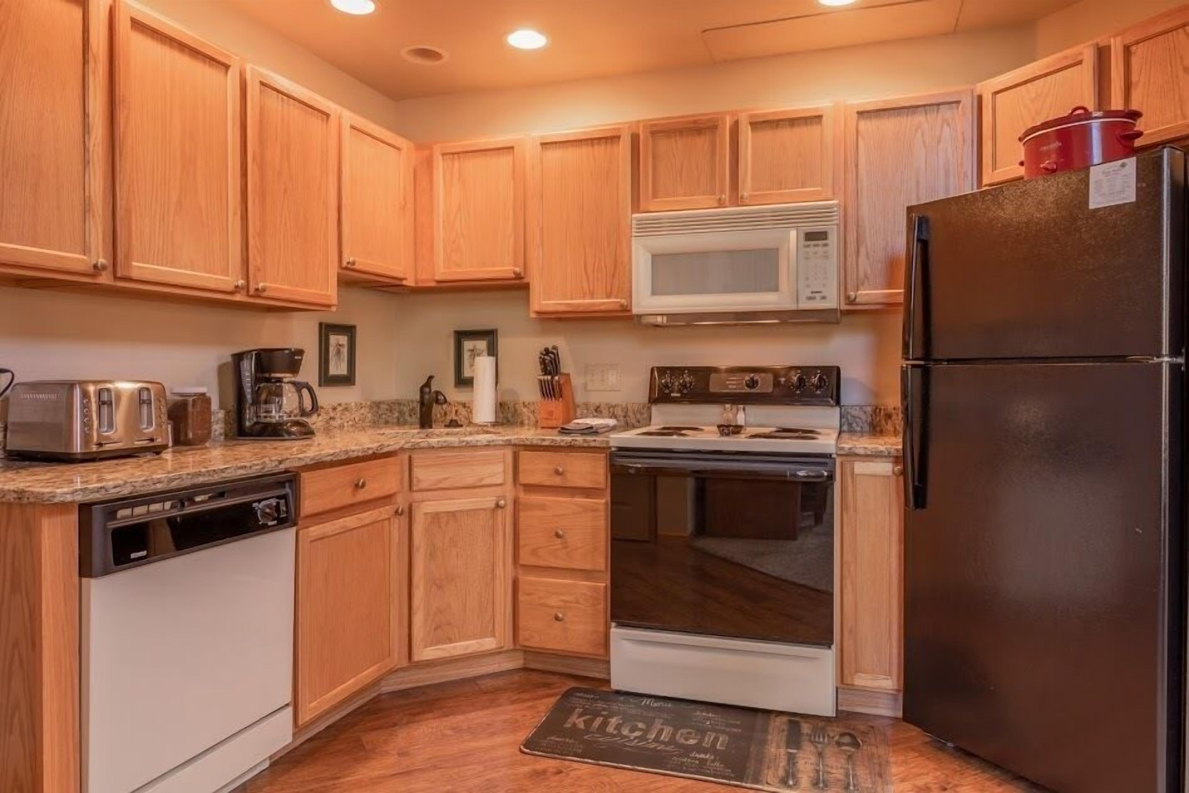 A kitchen with wooden cabinets, a microwave, a stove, a dishwasher, and a refrigerator.