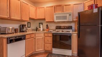 A kitchen with wooden cabinets, a microwave, a stove, a dishwasher, and a refrigerator.