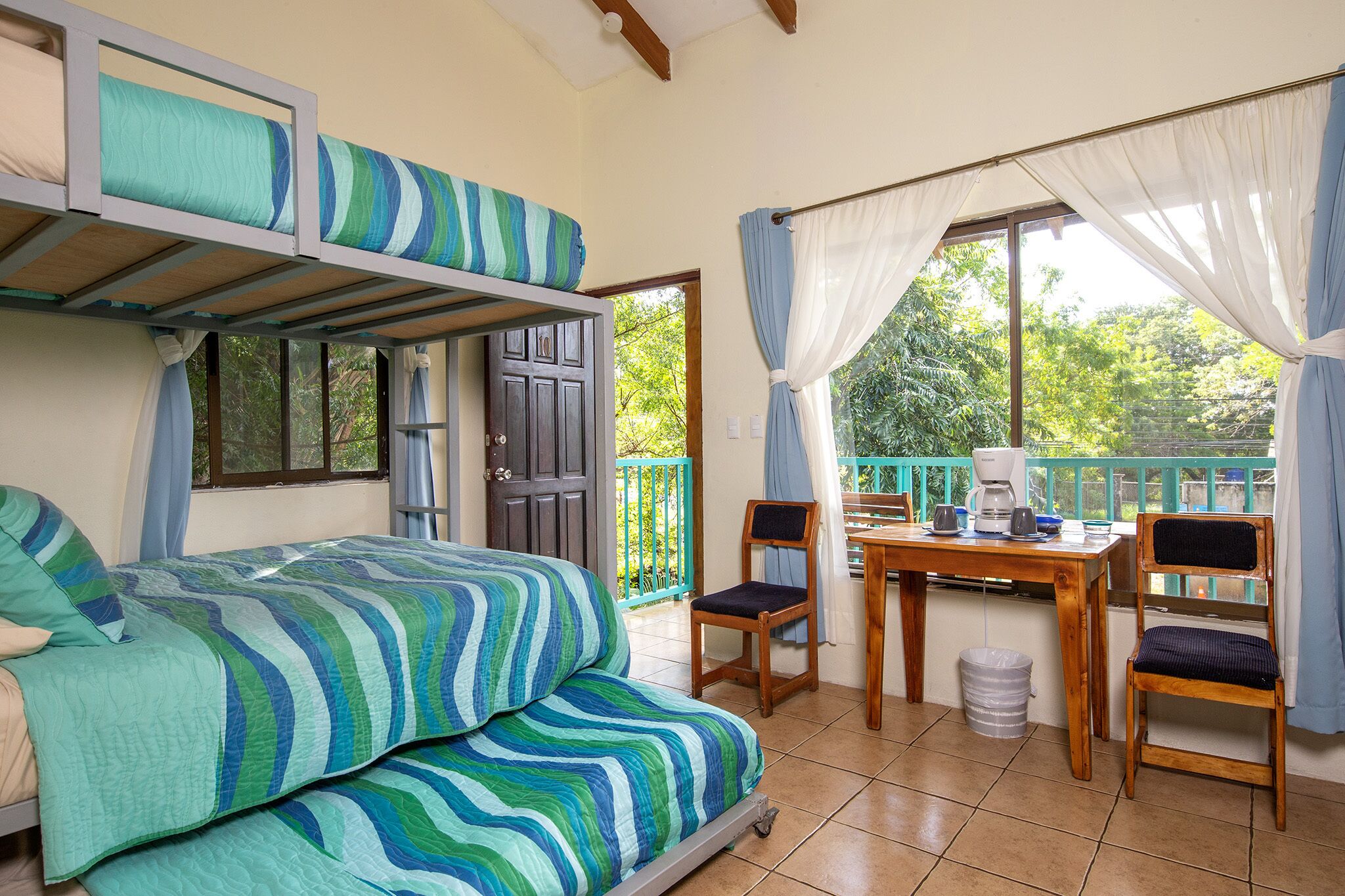 Une chambre avec un lit superposé, une table avec des chaises et une vue sur la verdure.