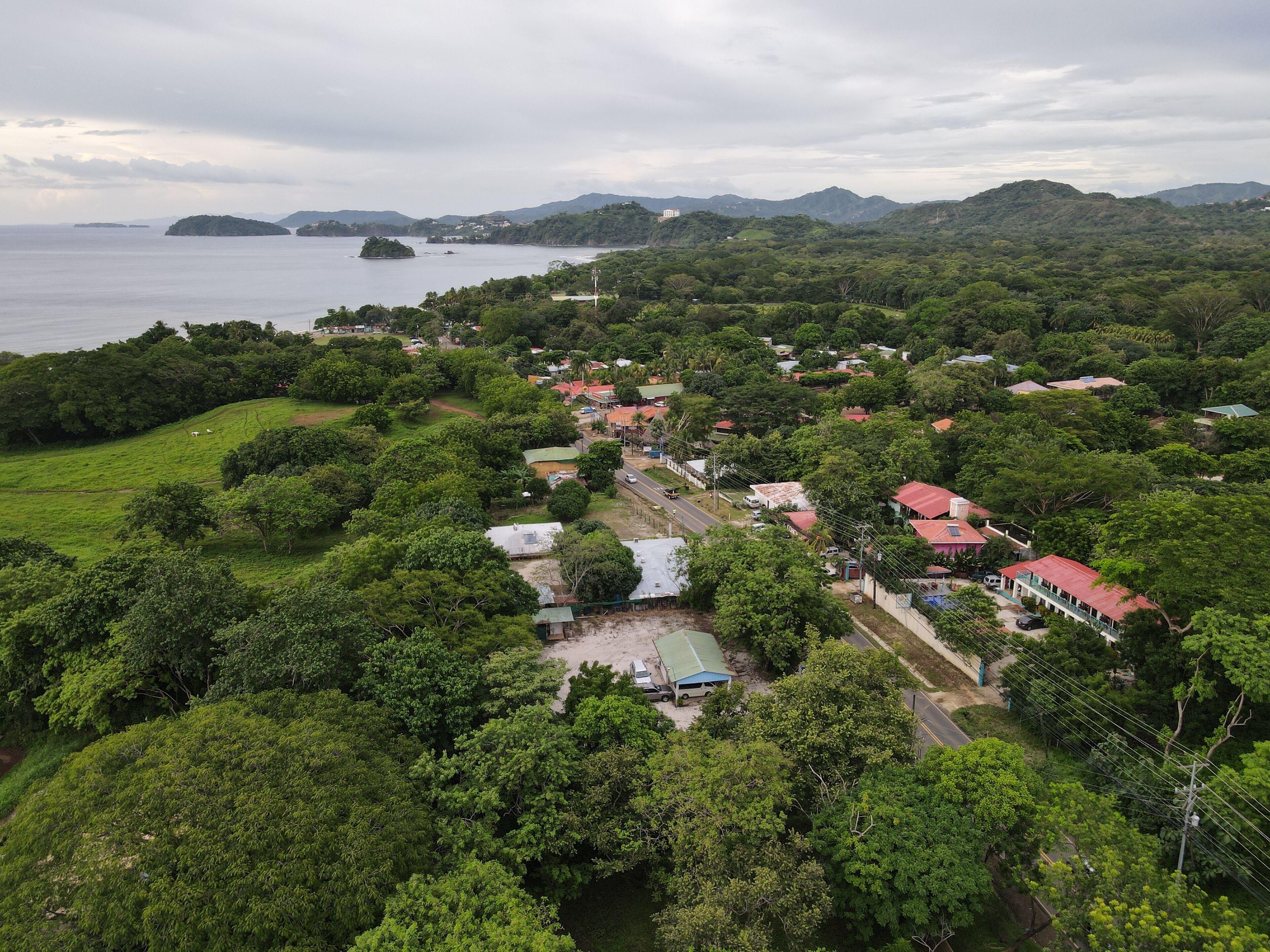 Un village côtier, avec une végétation luxuriante, des maisons aux toits rouges et une route qui mène à la mer.