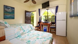 Habitación con dos camas, ventilador de techo, televisor, refrigerador y ventana con cortinas.