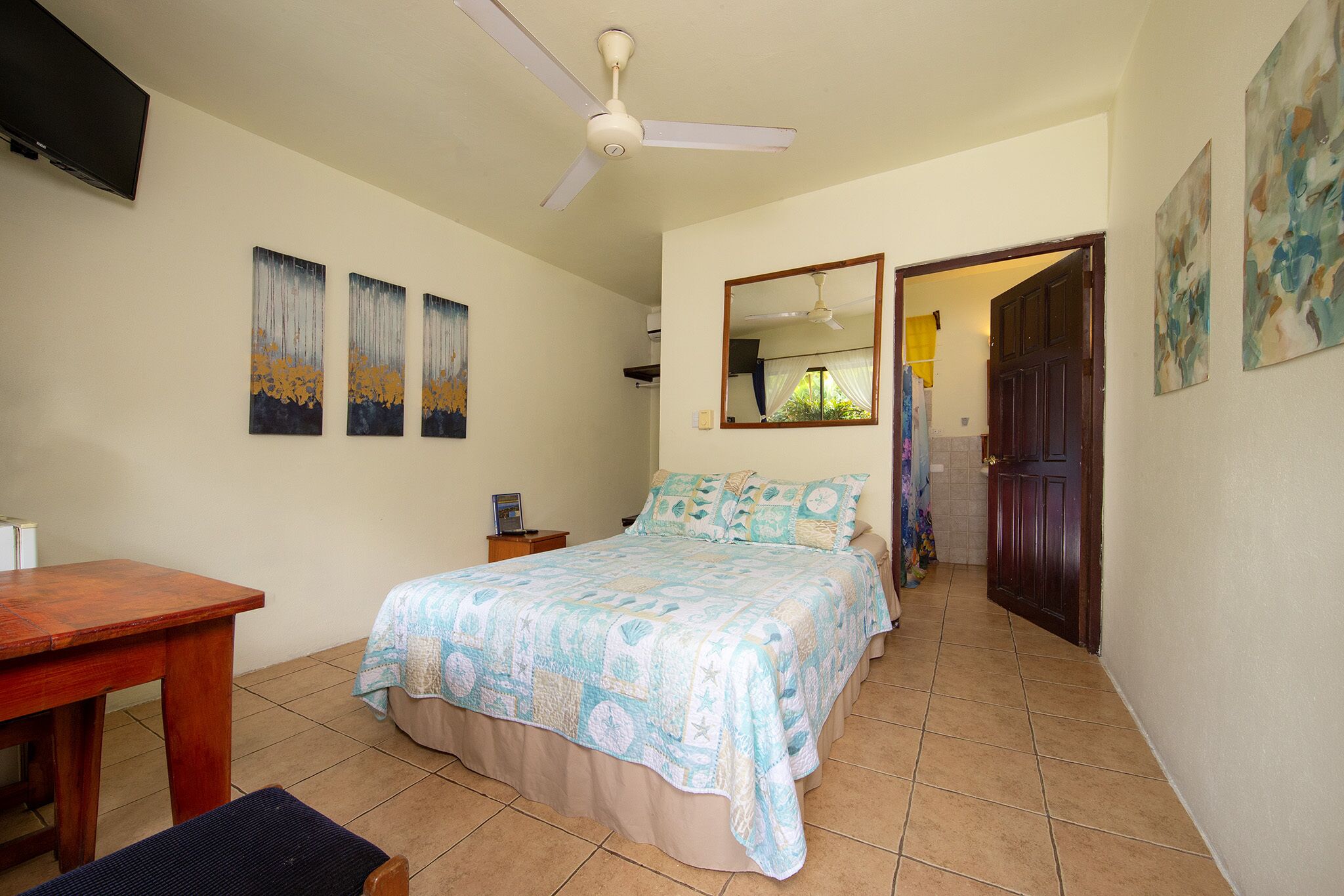 Une chambre à coucher avec un lit, un bureau et un ventilateur de plafond.