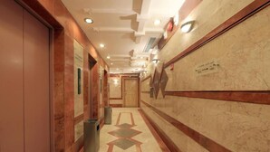 A corridor with marble flooring, a trash bin, and a door at the end. - Snood Al Aziziah (Makkah)