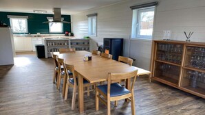 Une cuisine moderne avec un coin repas, un plancher en bois et un meuble vitré contenant de la vaisselle.