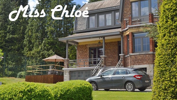 Une maison à deux étages avec un porche couvert, une voiture garée dans l’allée et un jardin bien entretenu.
