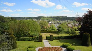 Un jardin bien entretenu, avec un chemin central, des haies soigneusement taillées et un parterre de fleurs circulaire.