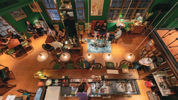 A restaurant with a central seating area, a bar, and a counter with a chef preparing food. - Originn (Taipei)