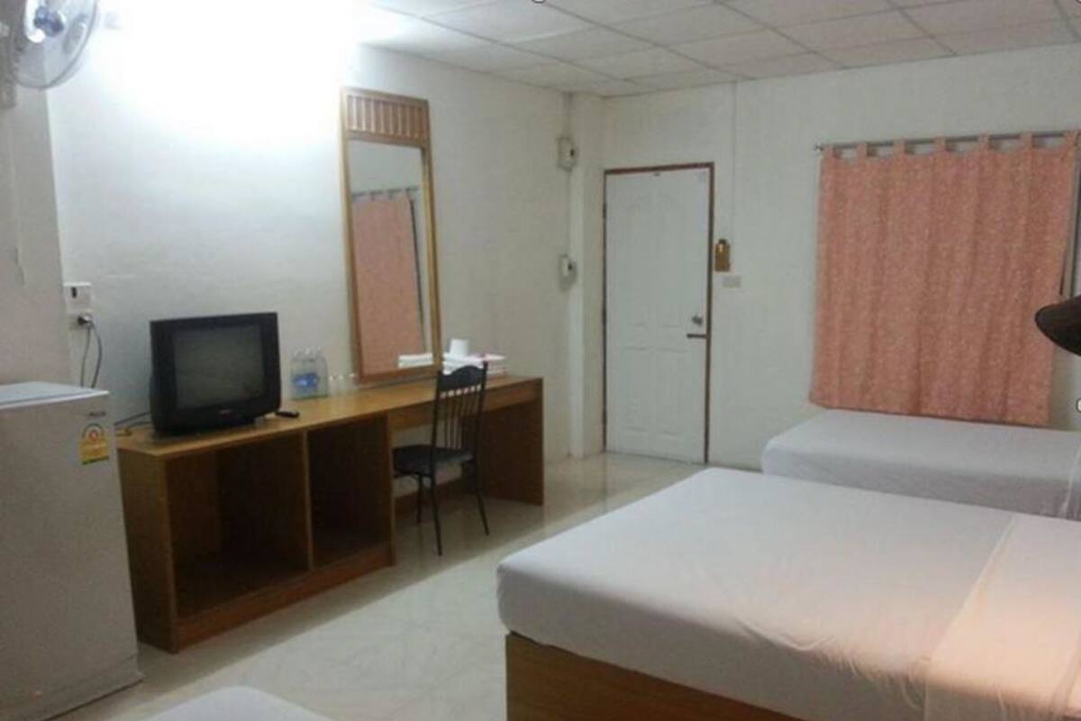 Una habitación de hotel con cama, escritorio con computadora, televisor y armario.