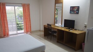 Een hotelkamer met een bed, een bureau met een computer, een stoel en een koelkast.