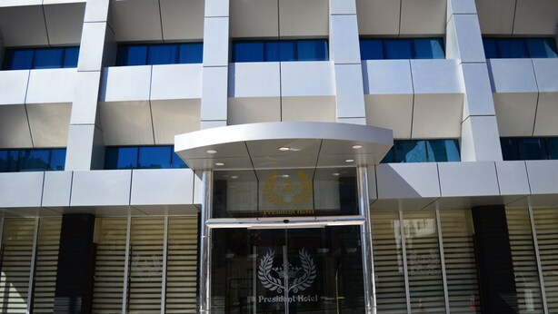Una entrada de hotel moderna con fachada de vidrio y un logotipo destacado.