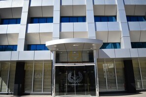 A modern hotel entrance with a glass facade and a prominent logo. - President hotel (Amman)