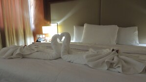 Una habitación de hotel con una cama bien hecha, una lámpara y un teléfono en la mesita de noche.