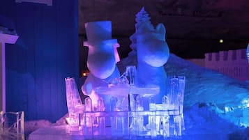 Una exhibición de esculturas de nieve con diversas figuras y estructuras, incluyendo una figura con bombín y un muñeco de nieve.