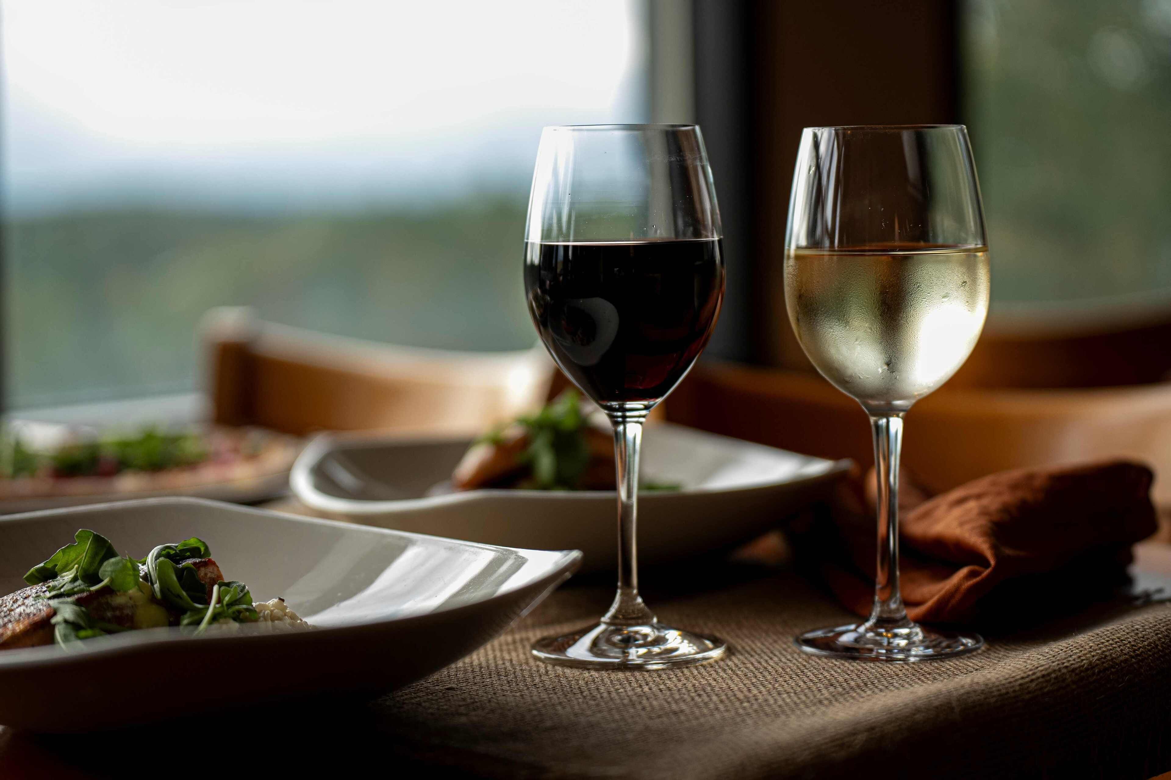 Deux verres à vin sont posés sur une table, offrant une vue sur l’extérieur.