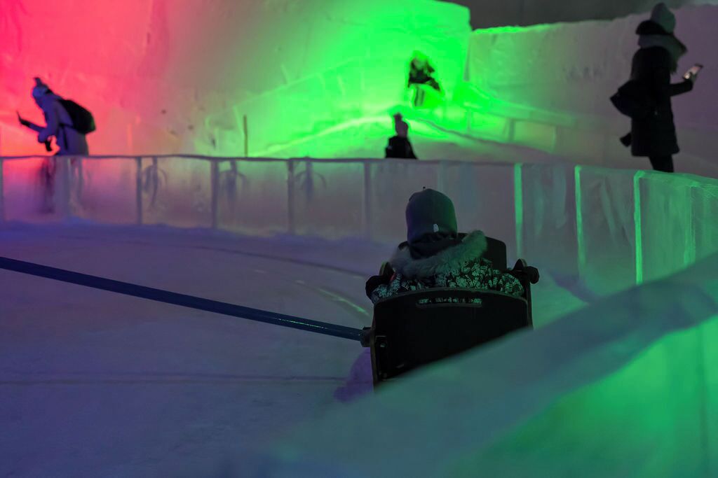 A person sledding on a snow-covered slope with a green-lit background.
