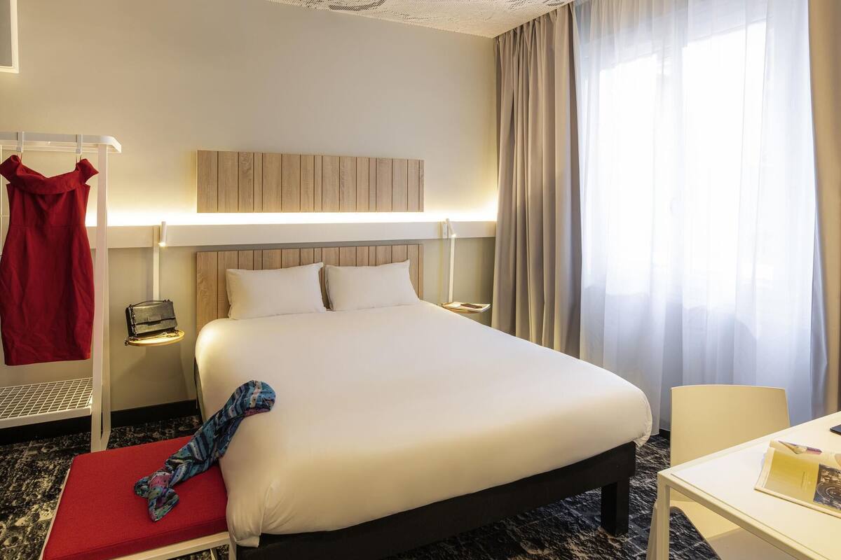 Una habitación de hotel con una cama grande, mesitas de noche, un escritorio y una silla.
