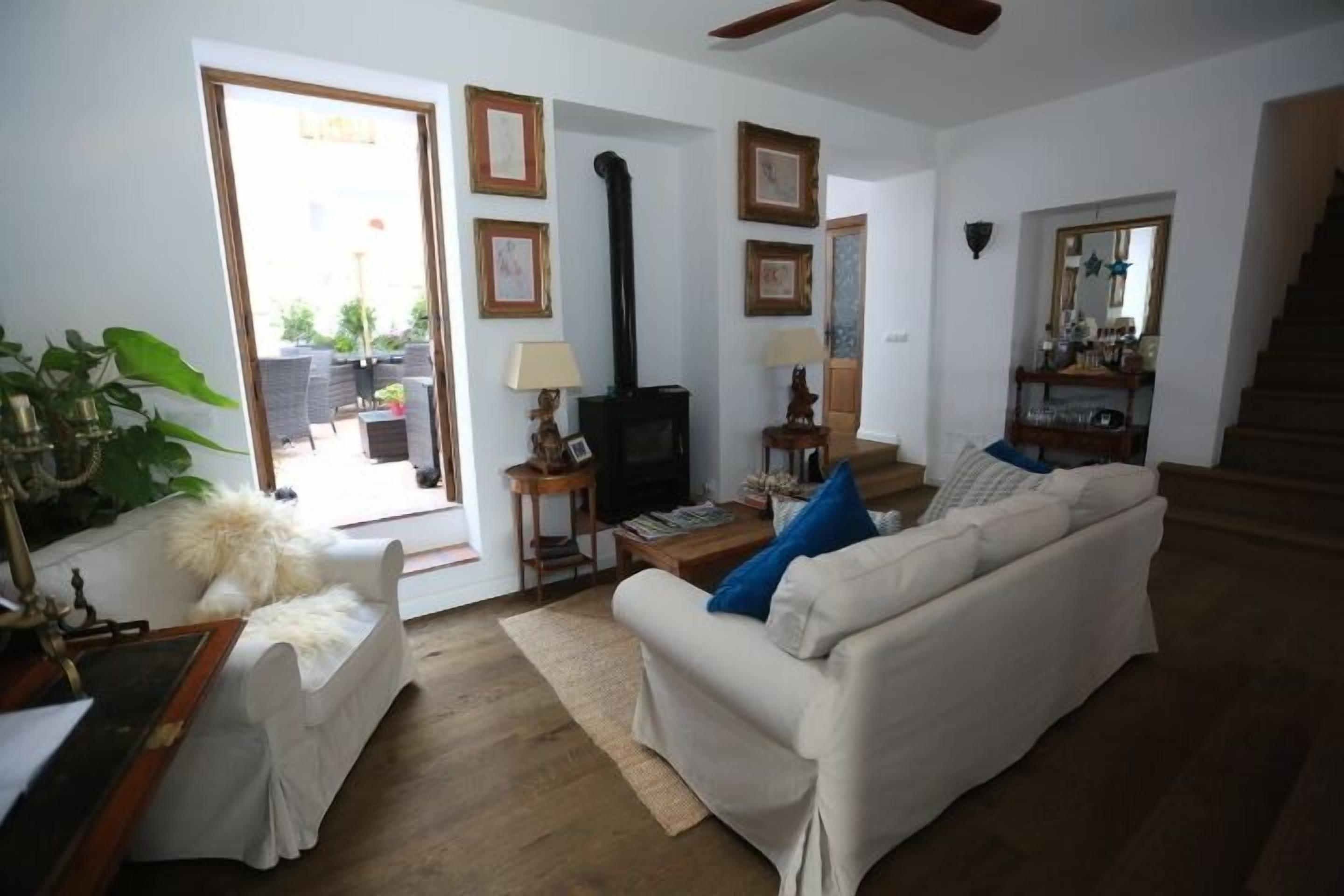 Sala de estar com sofá, mesa pequena, televisão e lareira. Escada leva a outro andar.