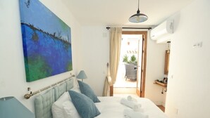 Ein Hotelzimmer mit Bett, einem Bild, einer Lampe und Blick nach draußen.