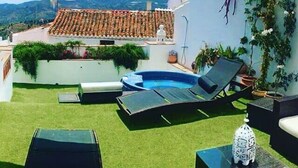 Eine Dachterrasse mit Swimmingpool, Liegestühlen und einer dekorativen Laterne.