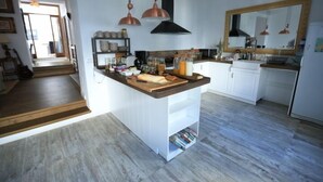 Eine moderne Küche mit weißen Schränken, einer Holztischplatte und kupfernen Pendelleuchten.