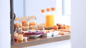 Ein reichhaltiges Frühstücksbuffet mit verschiedenen Speisen und Getränken, darunter Marmeladengläser und Orangensaft.