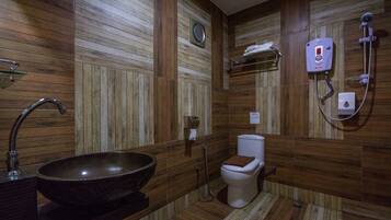 A bathroom with a wooden wall design, a large sink, a toilet, and a shower unit.