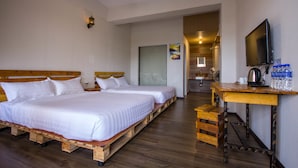 Een hotelkamer met twee houten bedden, een houten bureau met een waterfles, een televisie en een houten vloer.