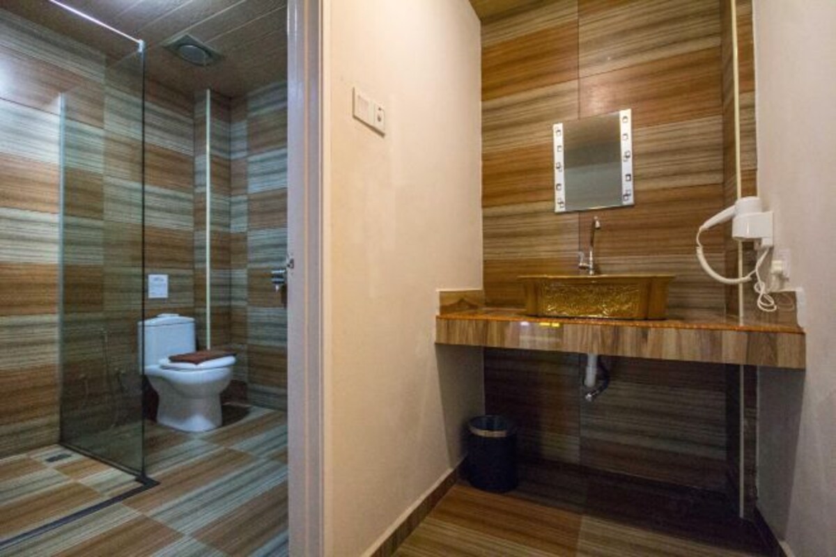 Une salle de bain moderne avec une douche à parois de verre, un meuble-lavabo en bois avec un miroir et des toilettes.