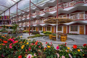 Un atrio a più livelli con balconi, un'area giardino centrale con fiori e un soffitto in vetro.