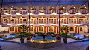 Een meerlaags hotel met balkons, een centrale binnenplaats met een fontein en een bordje waarop staat 'Thee Tuin'.