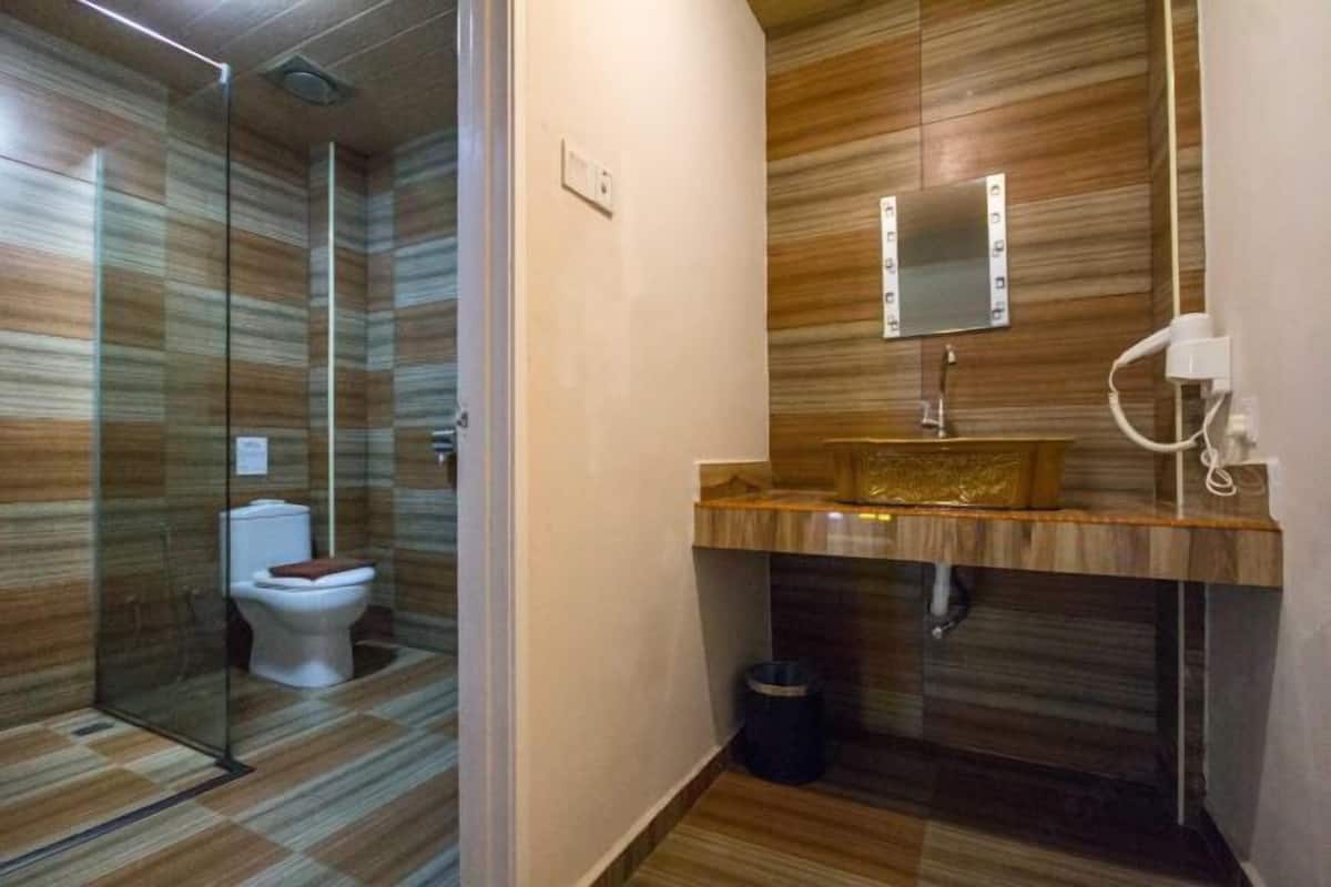 Un baño moderno con cabina de ducha de vidrio, tocador de madera con espejo y retrete.
