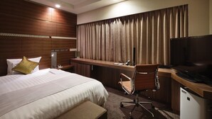 A hotel room with a bed, a desk, a television, and a small refrigerator. - JR East Hotel Mets Niigata (Niigata)