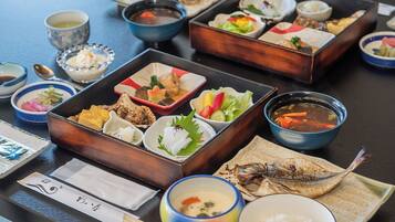 A variety of dishes arranged on a table, including bowls of soup, plates of fish, and other food items.