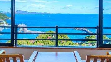 Una habitación con un amplio ventanal que ofrece vistas al mar y montañas a la distancia.
