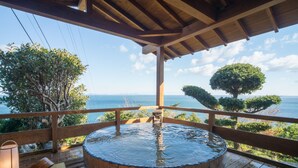 A wooden deck with a hot tub, wooden railings, and a view of the ocean. - Shinpachiya (Toba)