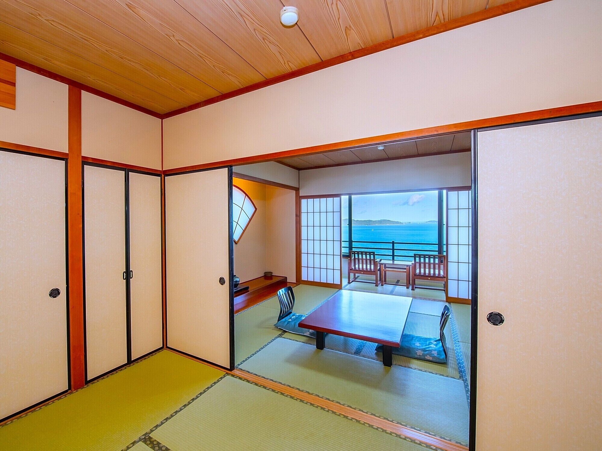 Una habitación japonesa tradicional con suelo de tatami, puertas correderas y vista al mar.