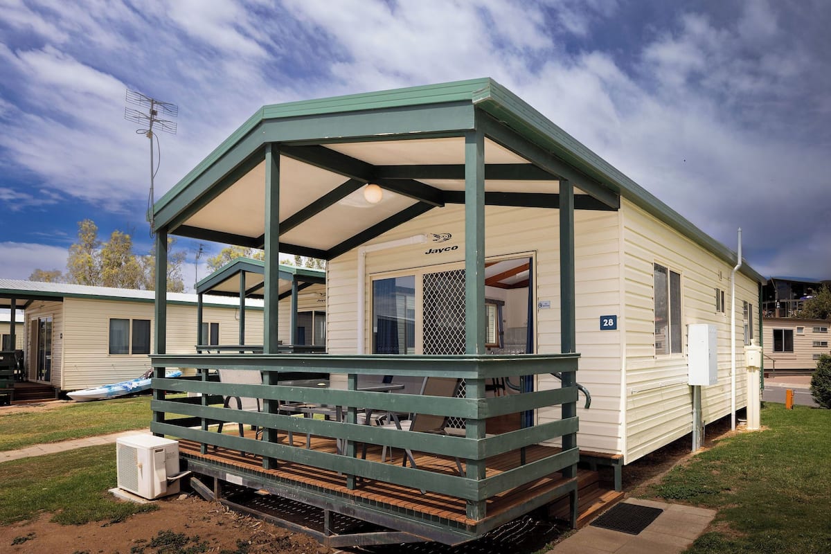 A mobile home with a covered porch, a number '28' sign, and a 'Javco' logo.