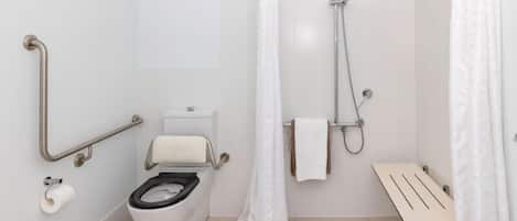 A modern bathroom with a toilet, shower, and grab bars.
