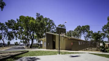 Un edificio con canestro da basket, un'area recintata e alberi.