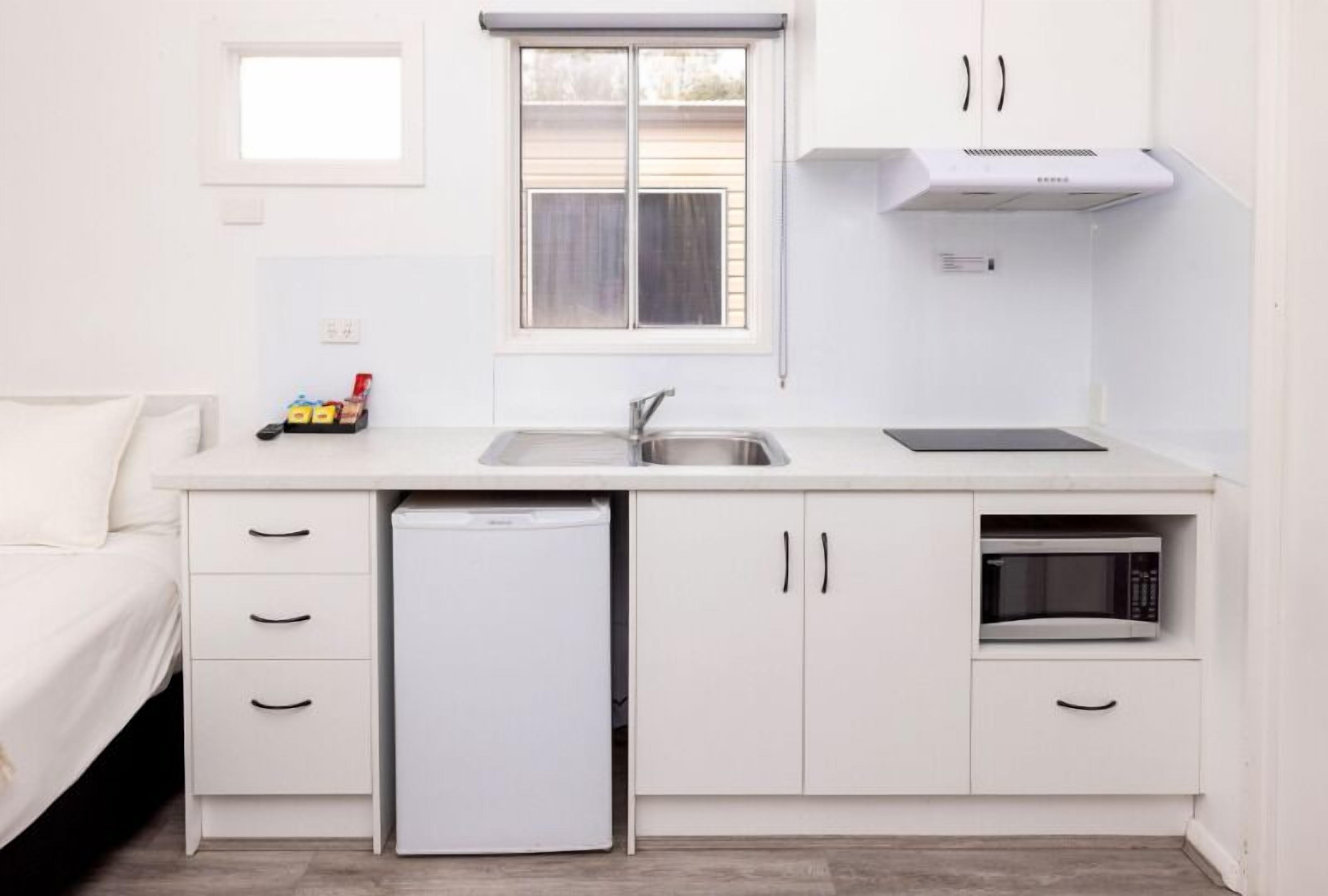 A compact kitchen with a sink, a microwave, and a refrigerator.