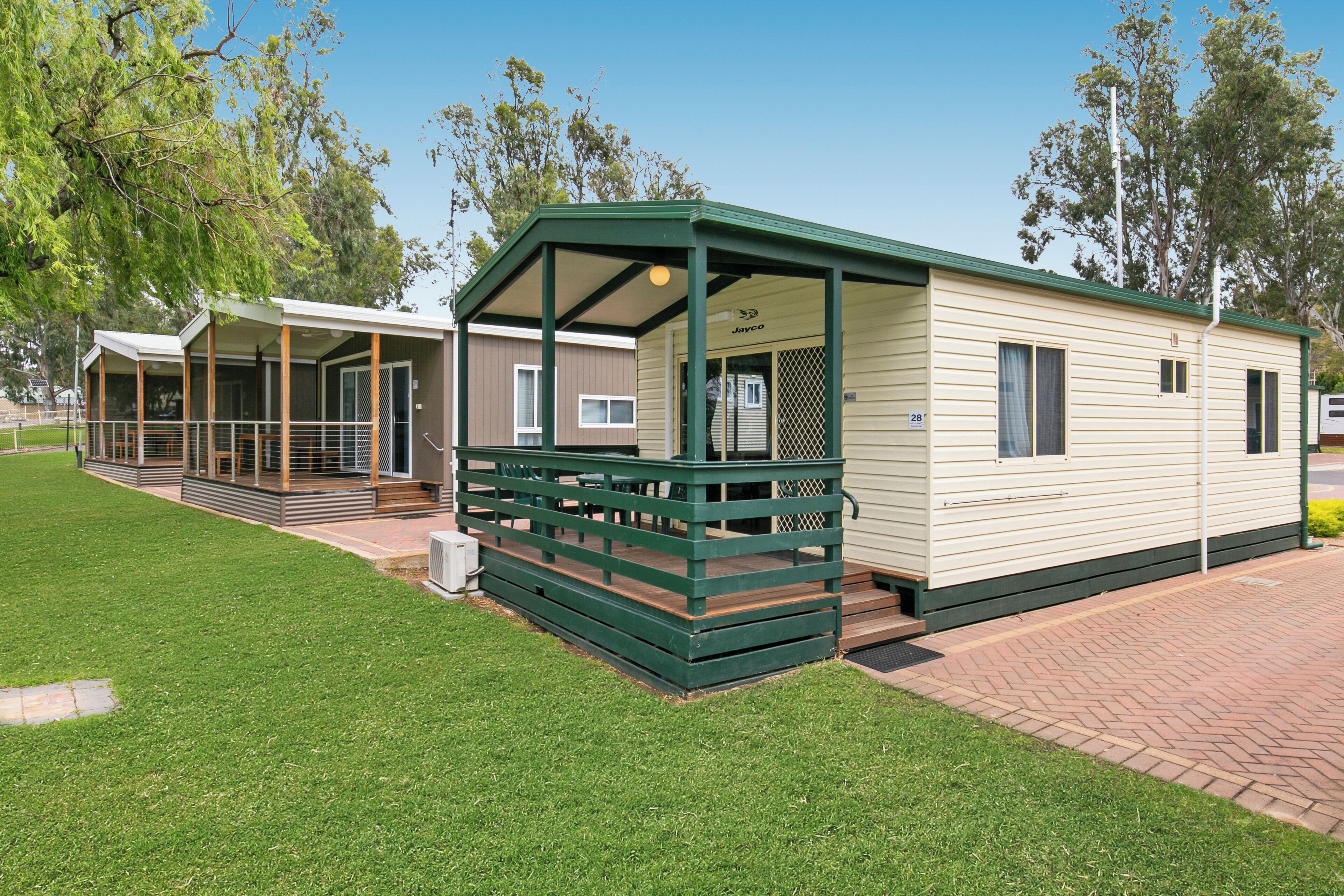 A mobile home with a covered porch and a fenced deck area.