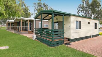 A mobile home with a covered porch and a fenced deck area.
