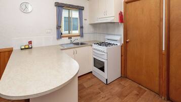 A compact kitchen with a sink, stove, and cabinets.