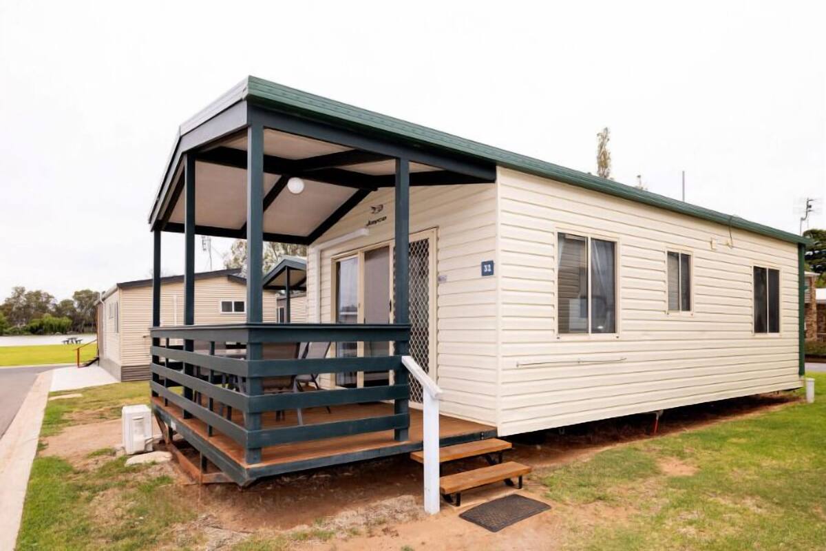 A mobile home with a covered porch and a small front yard.